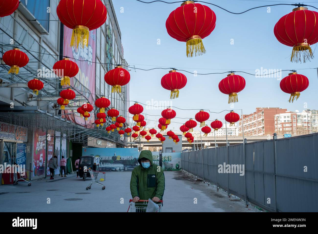 Die Verbraucher verlassen ein mit roten Laternen dekoriertes Einkaufszentrum nach dem Einkaufen, während das chinesische Frühlingsfest in Peking naht. 01-Jan-2024 Stockfoto