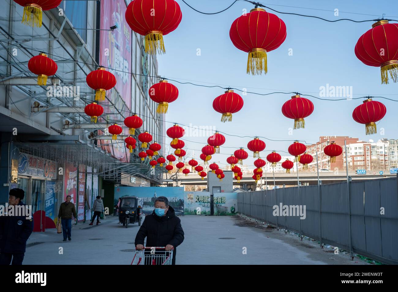 Die Verbraucher verlassen ein mit roten Laternen dekoriertes Einkaufszentrum nach dem Einkaufen, während das chinesische Frühlingsfest in Peking naht. 01-Jan-2024 Stockfoto
