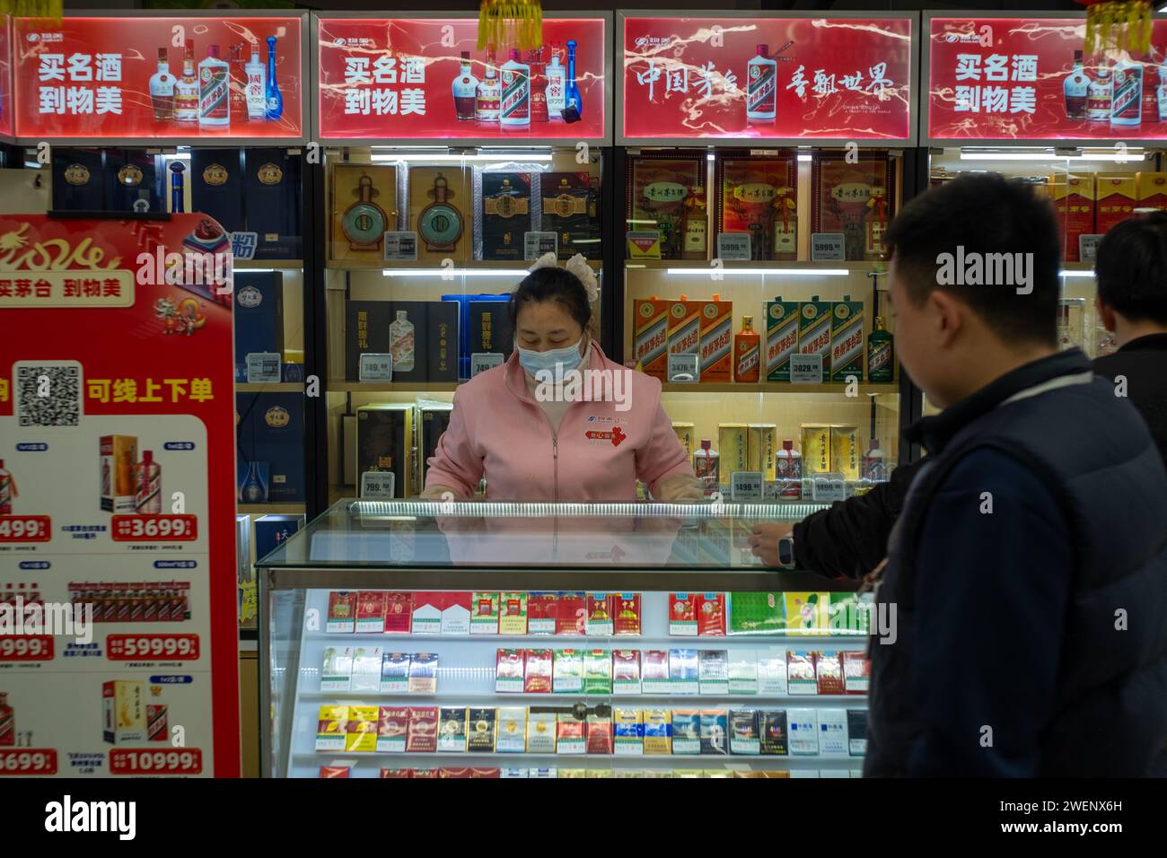 Chinesische Konsumenten kaufen an der Tabak- und Alkoholtheke in einem Einkaufszentrum in Peking, China. Januar 2024 Stockfoto