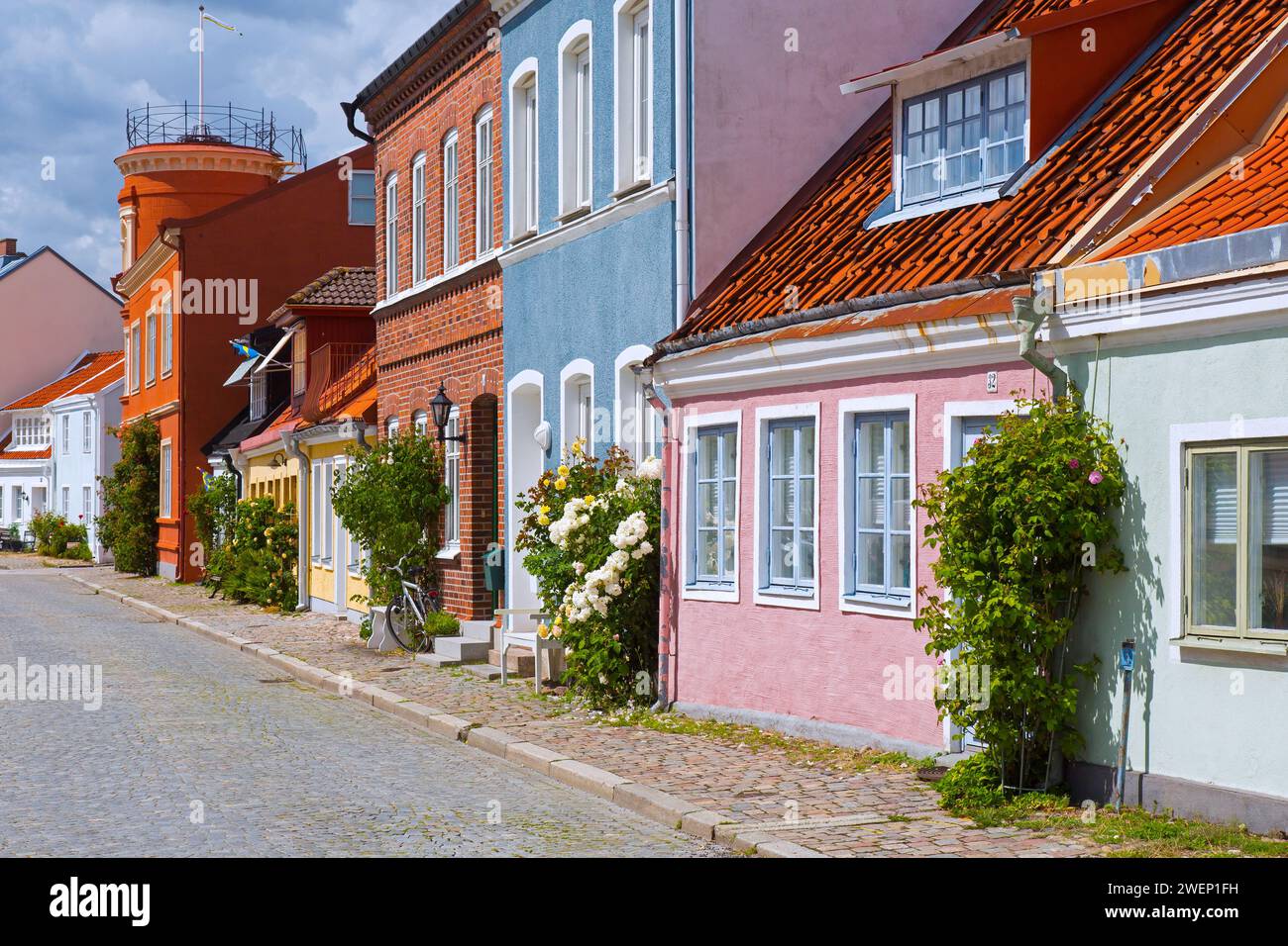 Kopfsteinpflasterstraße mit bunten Häusern in Pastellfarben in der Stadt Ystad im Sommer, Skåne / Scania, Schweden Stockfoto