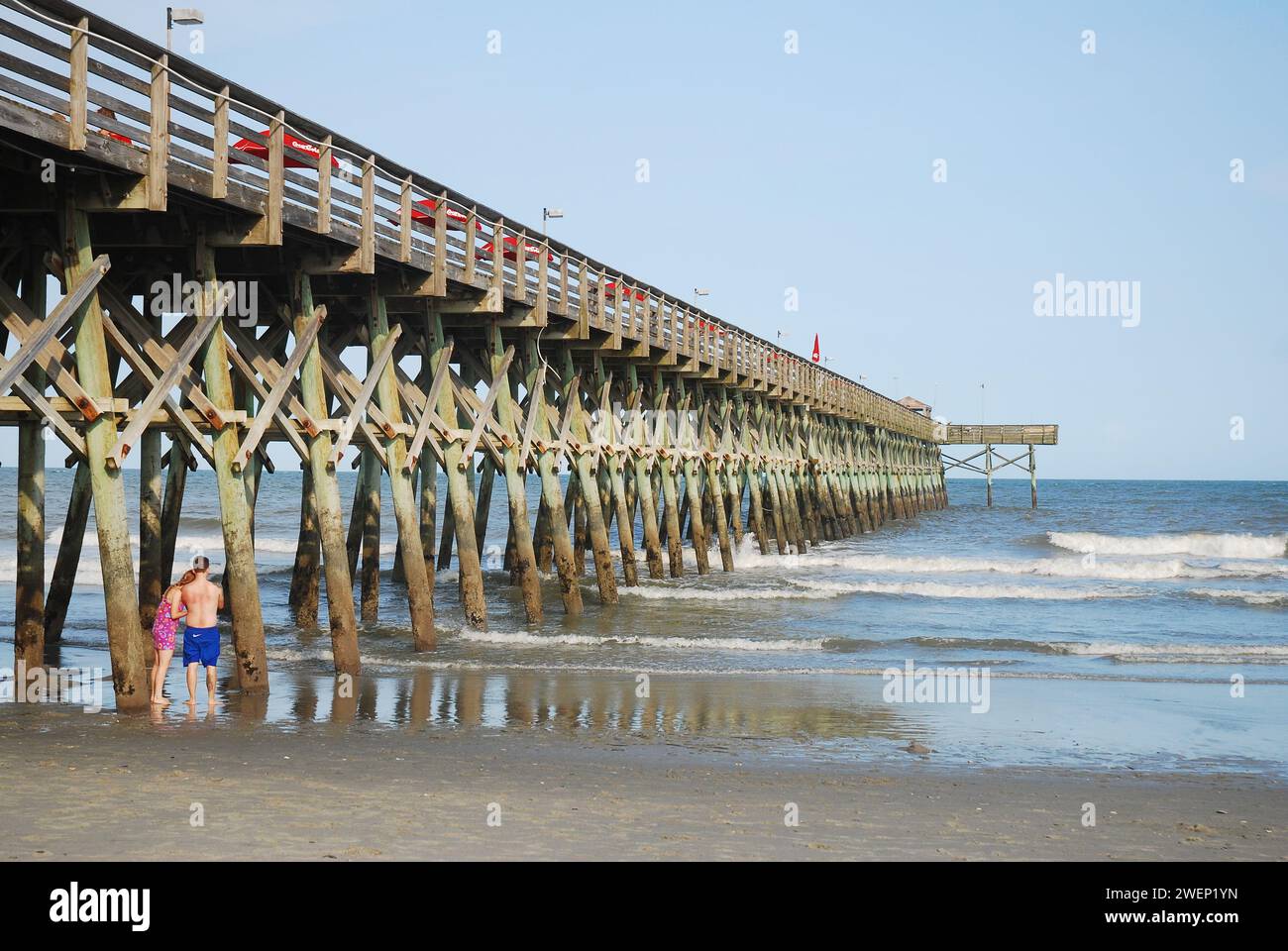 Ein Paar steht unter dem Second Avenue Pier, während die Wellen aus dem Atlantik in Myrtle Beach, South Carolina, hereinbrechen Stockfoto