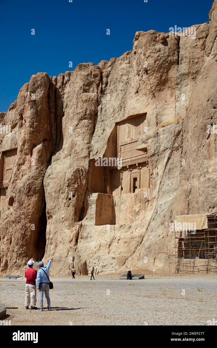 Touristen sehen das in Felsen gehauene Grab von Artaxerxes I., achämeniden König (465–425 v. Chr.) des Persischen Reiches. Naqsh-e Rostam Necropolis in der Nähe von Persepolis, Iran. Stockfoto