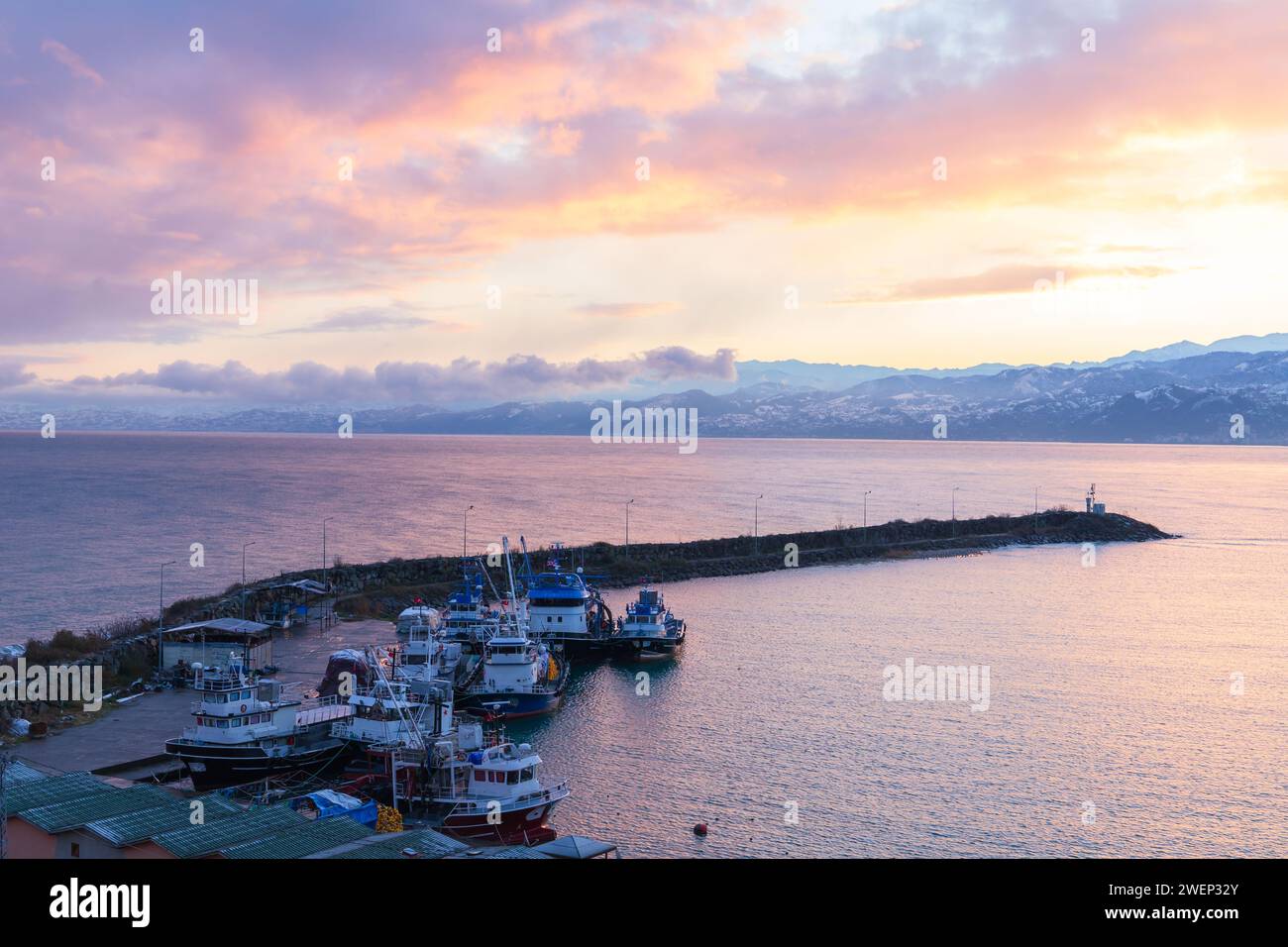 Blick auf die Küste mit Booten, die im kleinen Fischerhafen verankert sind. Schwarzmeerküste am Morgen. Arakli, Trabzon, Türkei Stockfoto