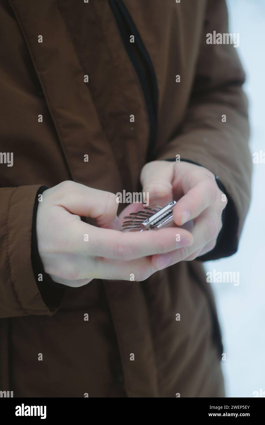 Eine Person im Freien, die bei Schnee einen kleinen Akustik-Player hält Stockfoto