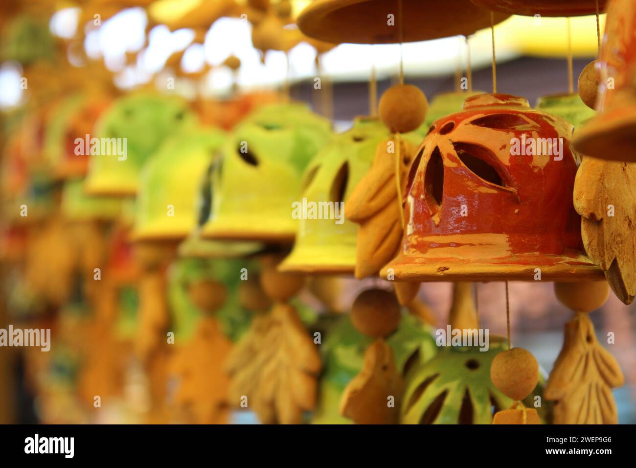 Mehrere Glockendekorationen mit Blattmotiven, die zart an eleganten Haken aufgehängt sind Stockfoto