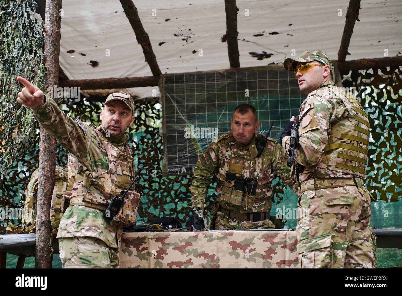 Eine gut ausgebildete Militäreinheit organisiert eine taktische Mission, während sie während einer Besprechung eine Militärkarte studiert Stockfoto