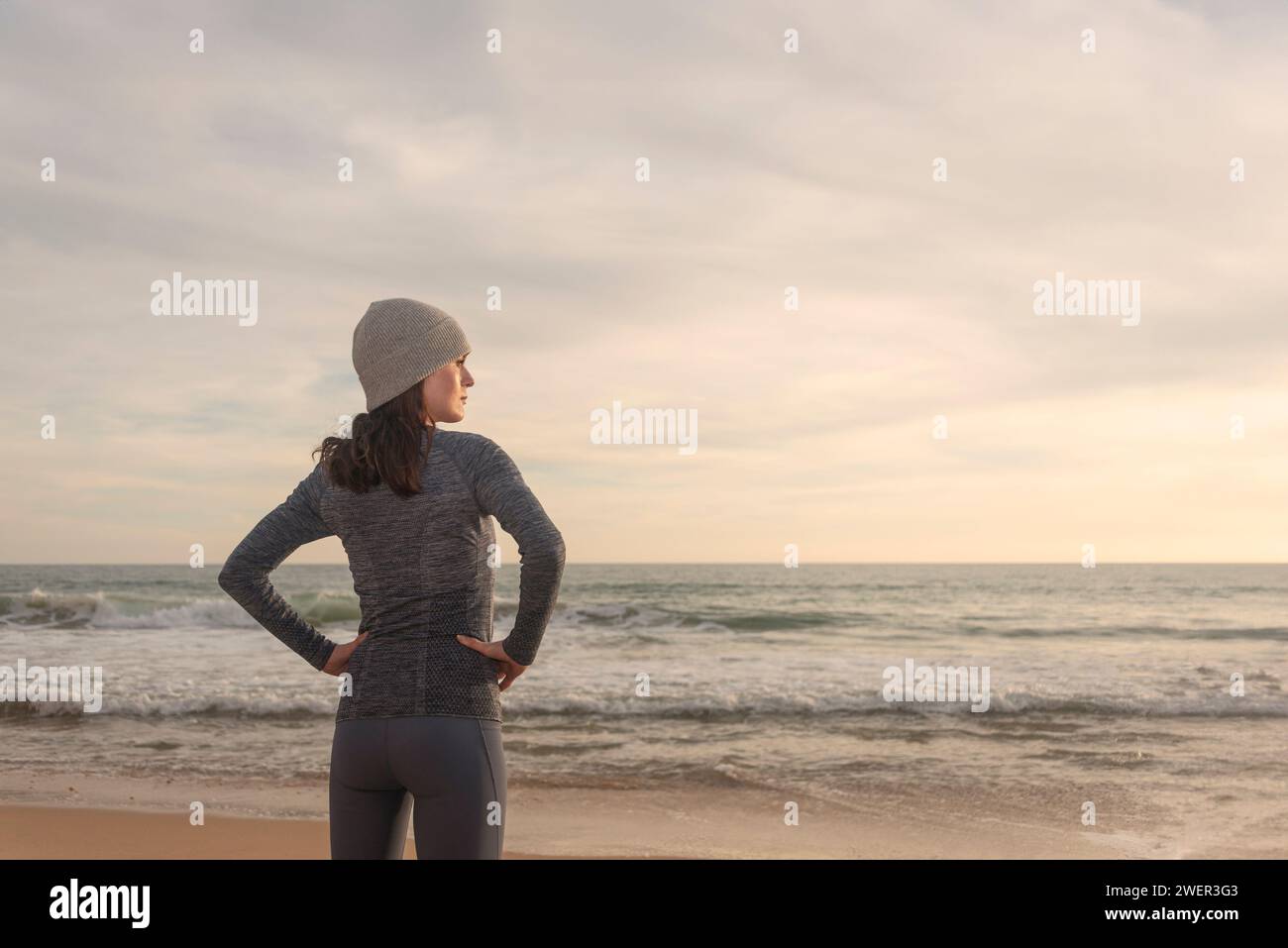 Sportliche Läuferin, die sich ausruht und nach dem Laufen am Strand aufs Meer blickt Stockfoto