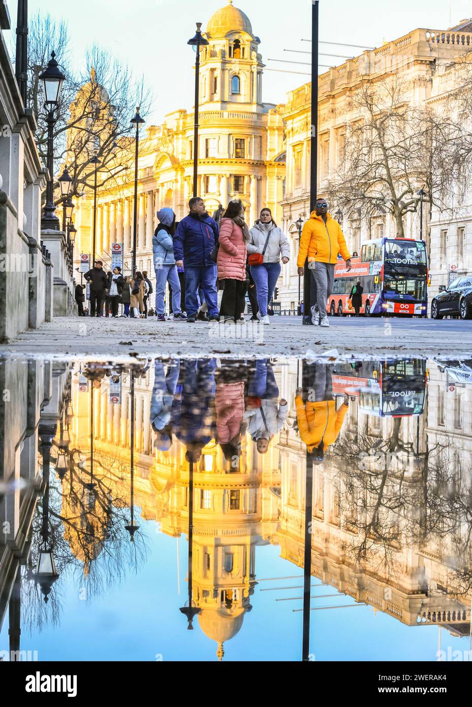 London, Großbritannien. Januar 2024. Fußgänger auf Whitehall spiegeln sich in einer großen Pfütze vom Regen der letzten Nacht. Nach starken Regenschauern über Nacht sah die Hauptstadt bis heute Abend Sonnenschein und klaren Himmel. Quelle: Imageplotter/Alamy Live News Stockfoto