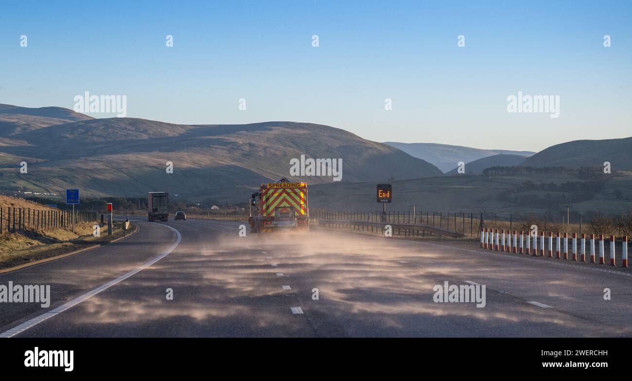 Streuwagen streuen Salz auf der Südseite der Autobahn M6 zwischen Shap und Tebay an einem kalten Winternachmittag in Cumbria, Großbritannien. Stockfoto