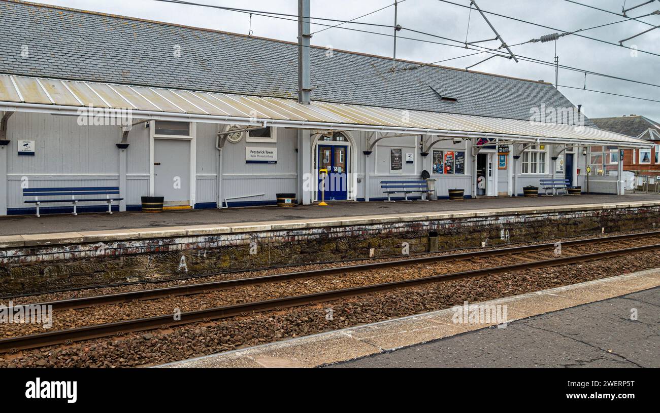 Bahnhof in Prestwick Town, South Ayshire, Schottland, zeigt Eisenbahnlinien, Freileitungen, Plattform, Bänke, Poster, Türen, Vordach und Schilder Stockfoto