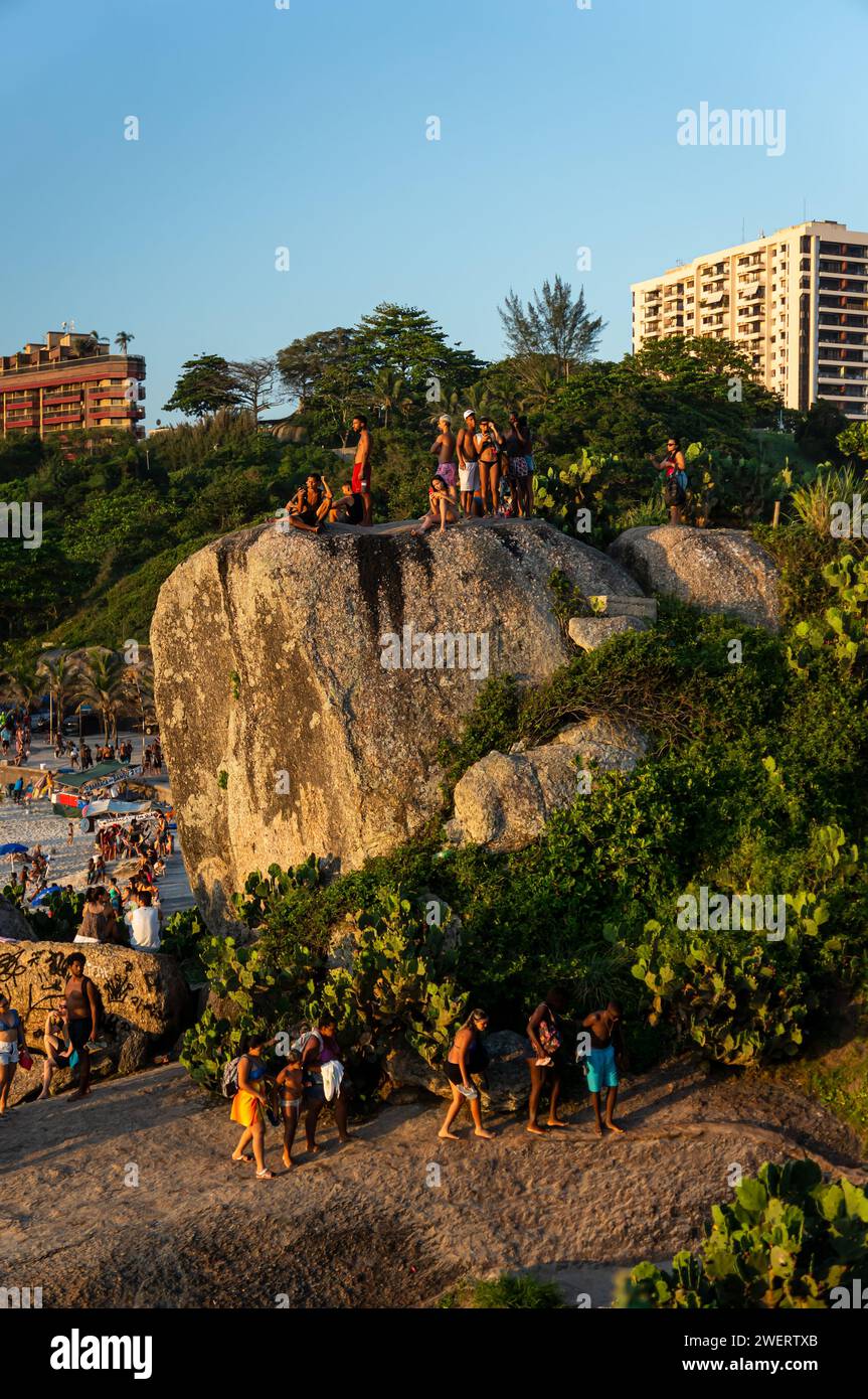 Die Leute klettern auf den Arpoador-Felsen (Pedra do Arpoador), um einen guten Ort zu finden, um den Sonnenuntergang über dem Atlantischen Ozean im Bezirk Ipanema zu bewundern. Stockfoto