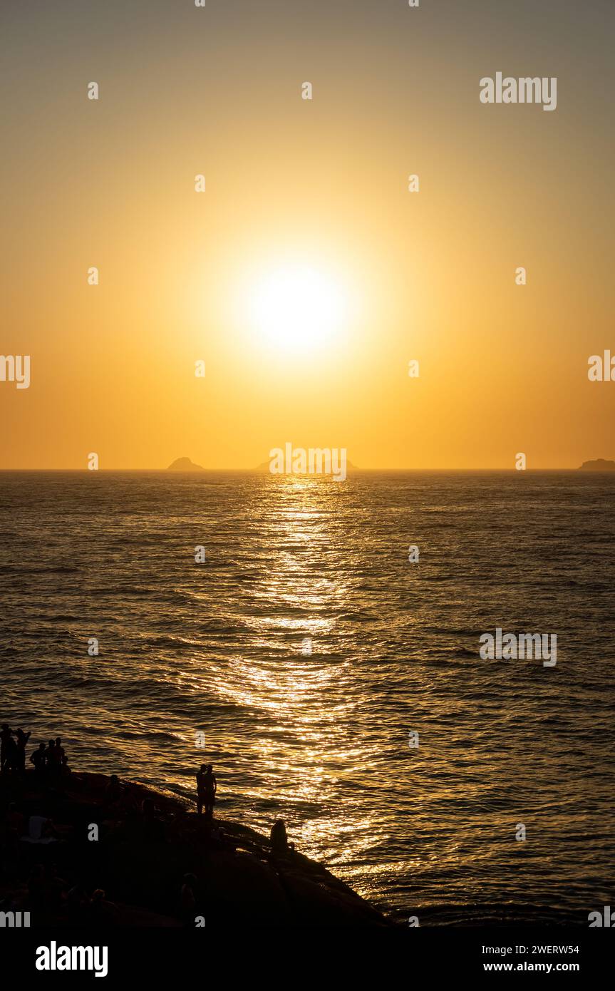 Goldener Sonnenuntergang goldener Himmel Blick über den Atlantik, wie von der Felsenhalbinsel Arpoador im Bezirk Ipanema unter dem sonnigen blauen Himmel am Sommernachmittag gesehen. Stockfoto