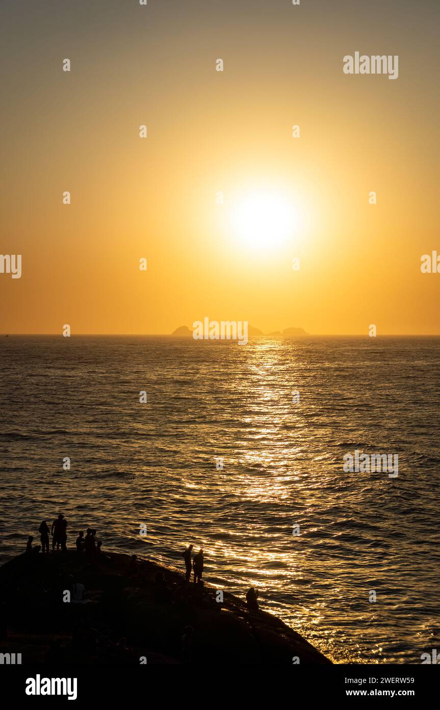 Goldener Sonnenuntergang goldener Himmel Blick über den Atlantik, wie von der Felsenhalbinsel Arpoador im Bezirk Ipanema unter dem sonnigen blauen Himmel am Sommernachmittag gesehen. Stockfoto