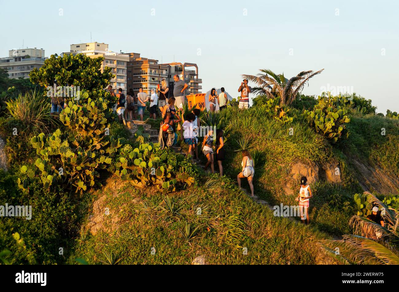 Die Leute klettern auf den Arpoador Felsen, um am späten Nachmittag einen guten Platz zu haben, um die Sonne über dem Atlantik im Bezirk Ipanema unter blauem Himmel zu beobachten. Stockfoto