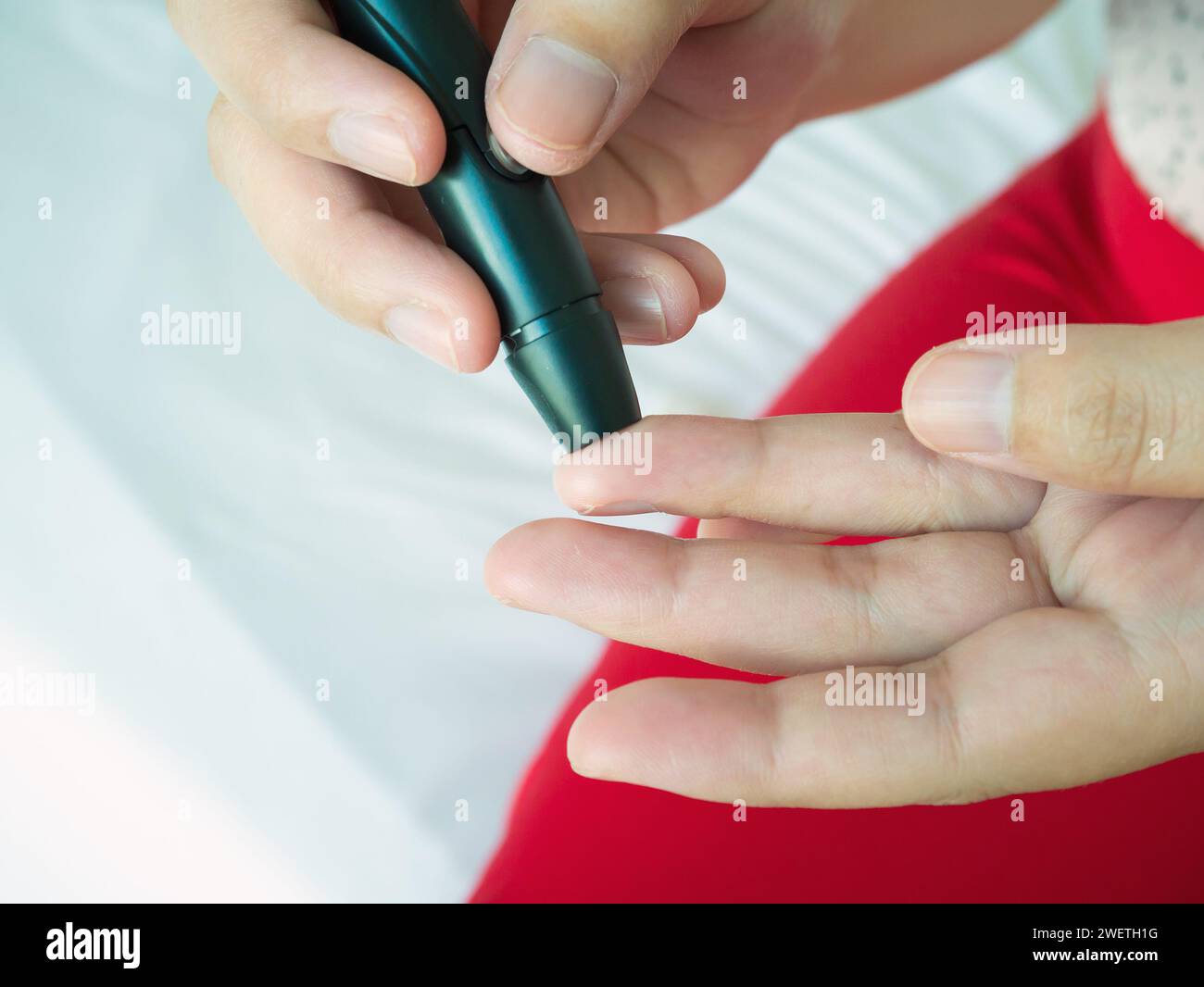 Frau mit lanzettfischchens am Finger, Diabetes Test überprüfung der Blutzuckerspiegel Stockfoto
