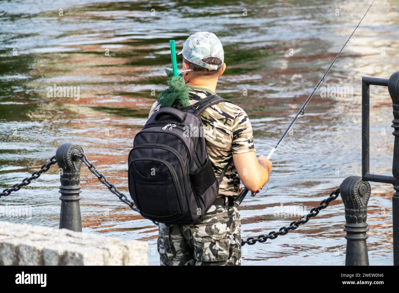 Ein Fischer in der Farbe einer Armee-Uniform mit einem Rucksack auf dem Rücken Stockfoto