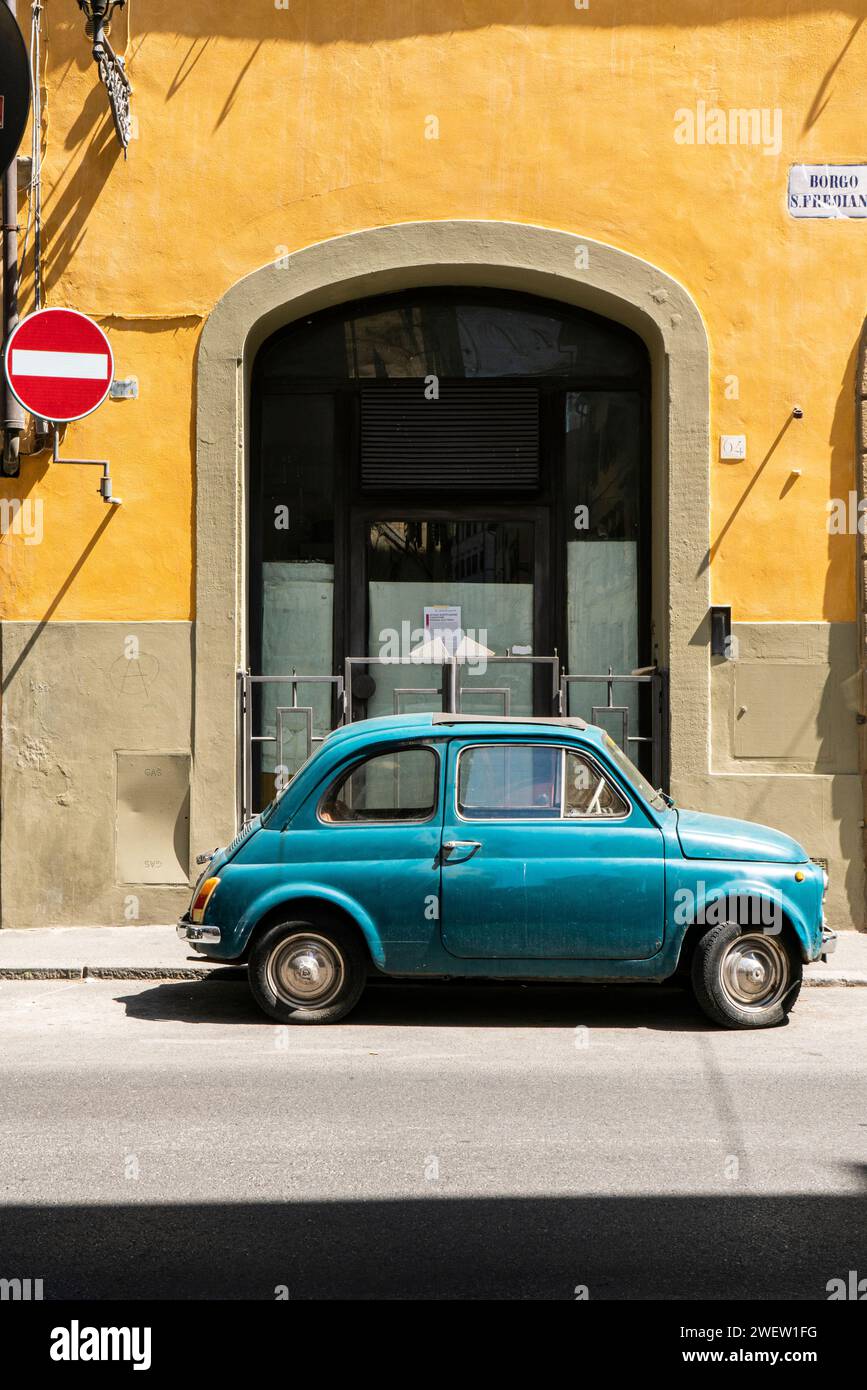 Blauer Fiat 500 parkt vor einem alten palazzo mit gelber Fassade im Stadtteil Oltrarno von Florenz, Toskana, Italien Stockfoto