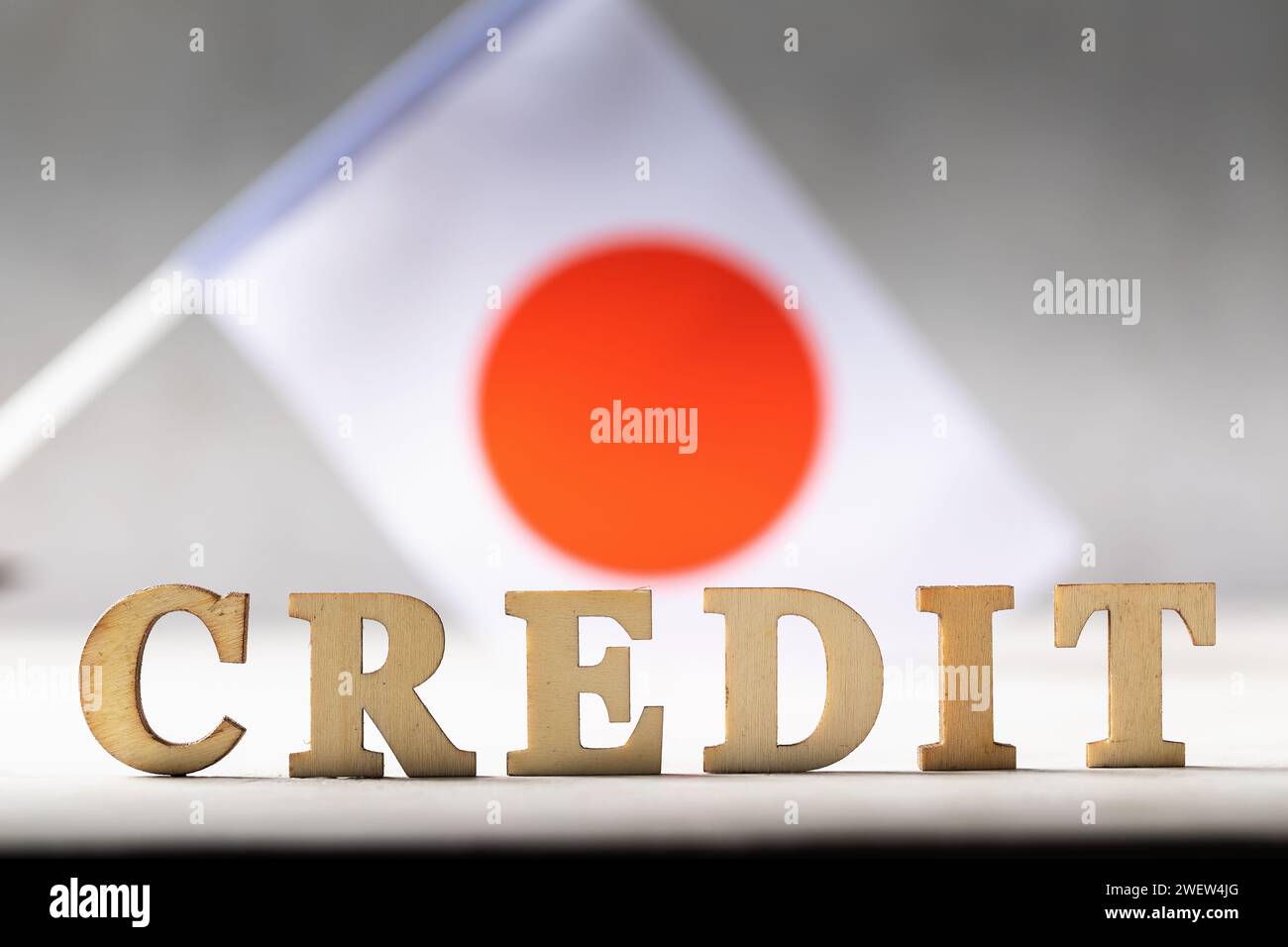 Text aus Holzbuchstaben und japanischer Flagge auf abstraktem Hintergrund, Konzept zum Thema der Schuldenlast des japanischen Volkes Stockfoto