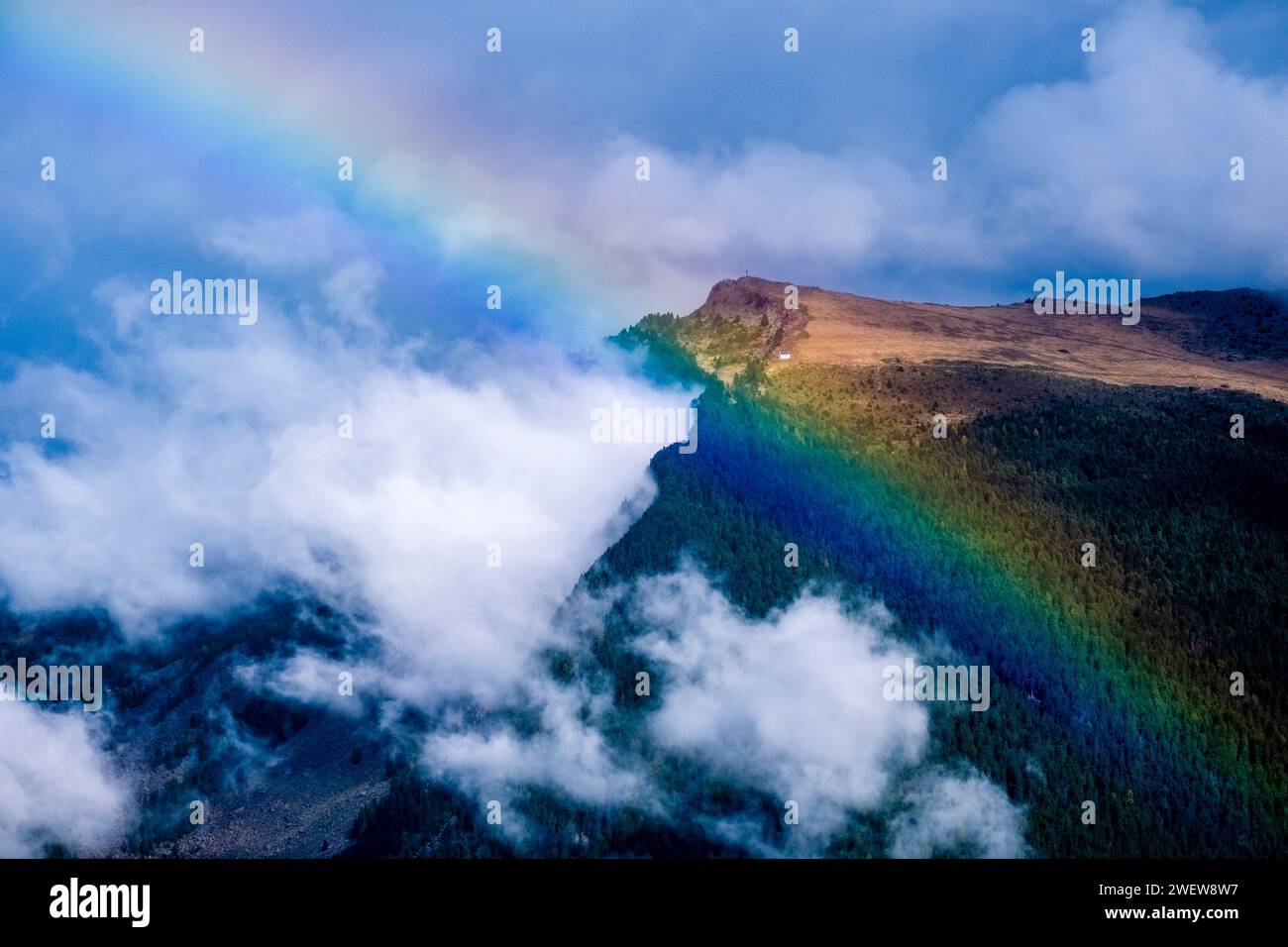 Regenbogen und aufsteigende Wolken nach einem Regenschauer auf dem Puflatsch-Plateau. Stockfoto