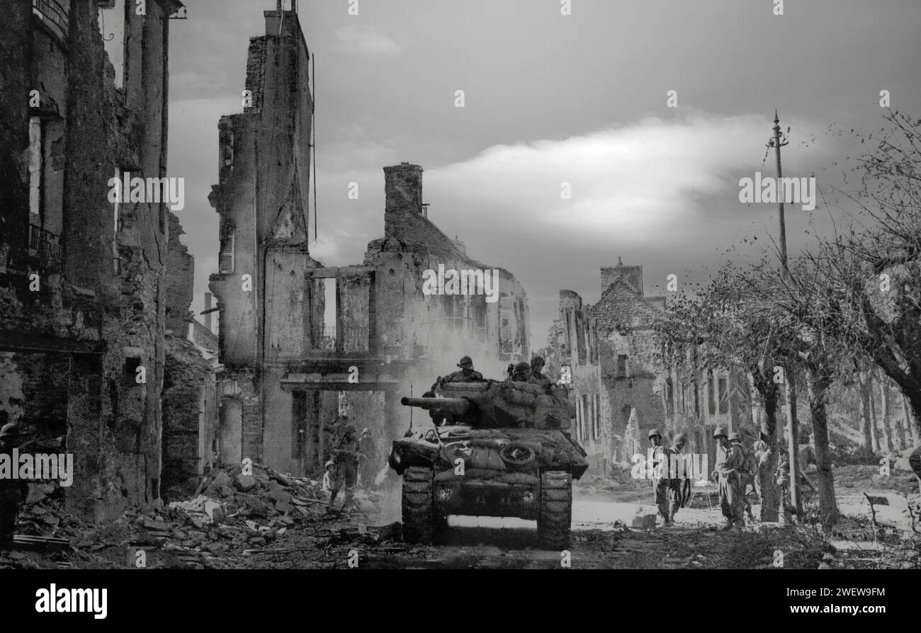 Ein alliierter Panzer wühlte gegen Ende des Monats nach dem D-Day am 6. Juni 1944, während des Zweiten Weltkriegs, durch die Überreste einer französischen Dorfstraße der Normandie. Stockfoto