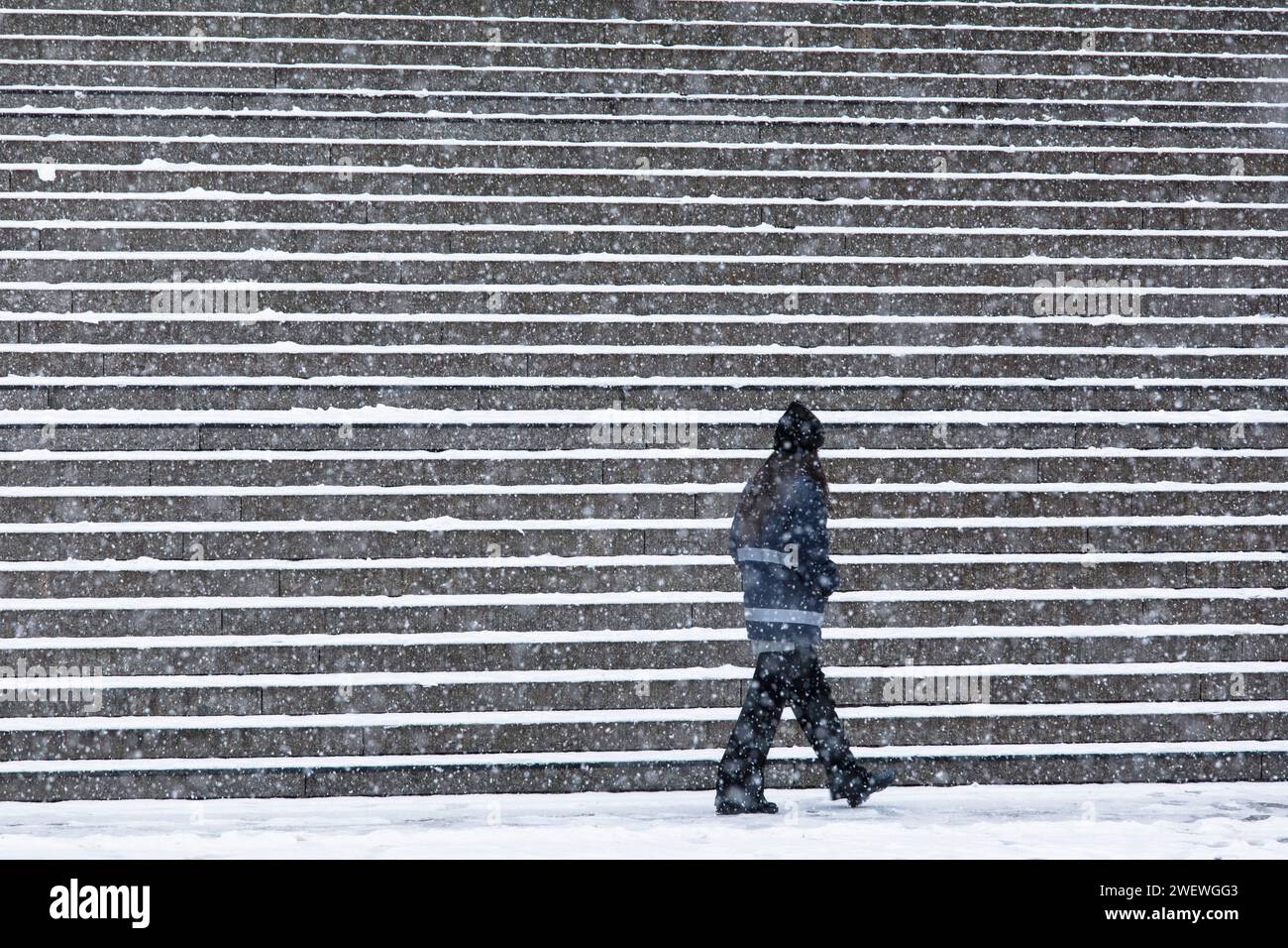 Person mit horizontal gestreifter Jacke vor der 70 Meter breiten Treppe vom Bahnhofsvorplatz zum Dom, Schnee, Winter, Köln, GE Stockfoto