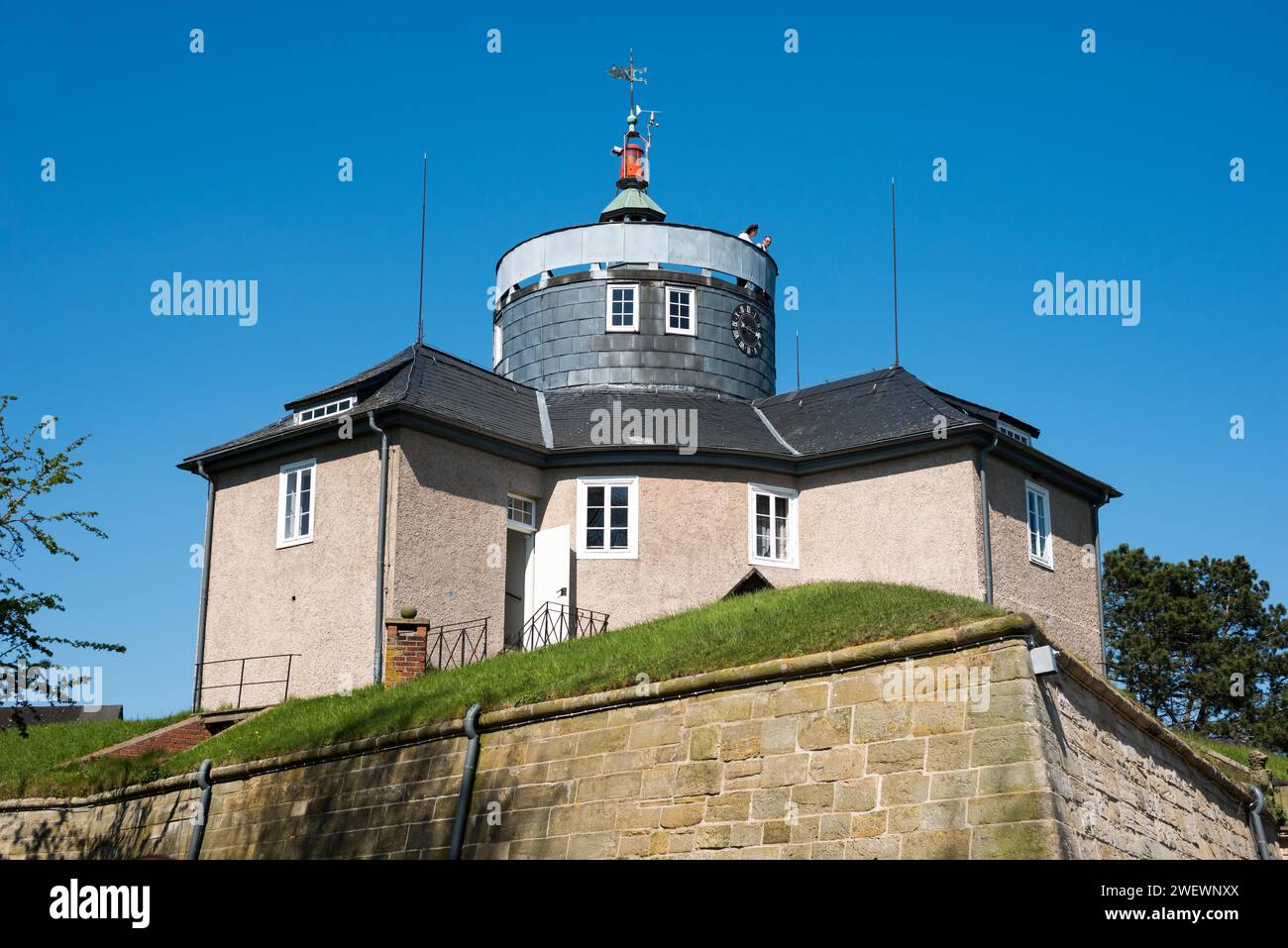Festung Wilhelmstein, historisches Schloss mit Turm, Turmuhr und Wetterfahne unter einem klaren blauen, wolkenlosen Himmel umgeben von grünem Gras, zwei Stockfoto