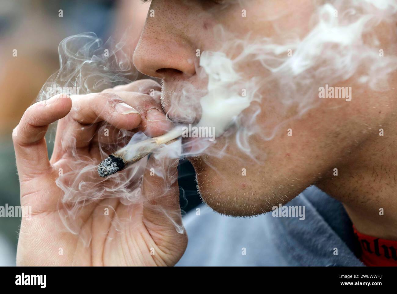 Ein Mann raucht einen Joint während einer Demonstration für legalen Marihuana-Konsum. Die Demonstranten fordern die Legalisierung und die sofortige Umsetzung Stockfoto