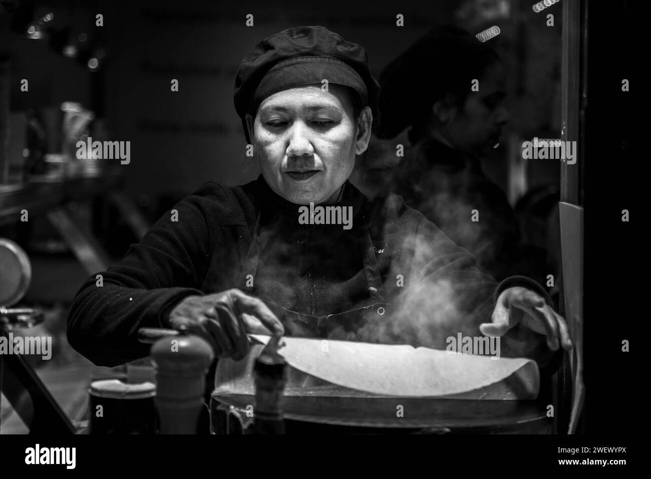 Küchenchefin mittleren Alters, die einen Crepe in einem lokalen Street-Food-Geschäft im Viertel Montmartre in Paris, Frankreich, Europa zubereitet Stockfoto