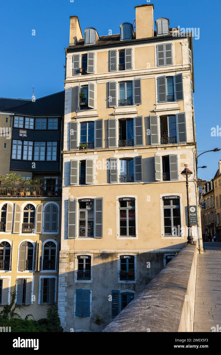 Ein typisches altes mehrstöckiges Haus mit raumhohen Fenstern und Fensterläden in der Nähe der Brücke. Pau, Pyrénées-Atlantiques, Frankreich. Stockfoto