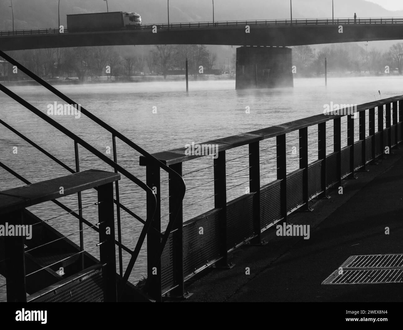 Die seine bei Vernon, Normandie, Frankreich. | Schwarzweißbild eines nebeligen Flusses mit einer Brücke im Hintergrund, von einem Metallgeländer aus gesehen. Stockfoto