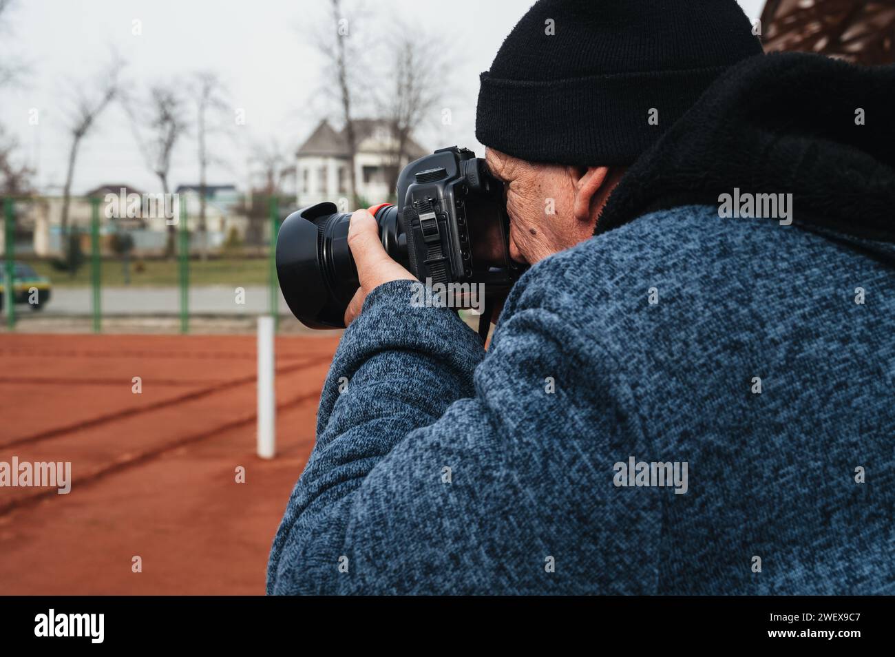 Ein älterer Mann, professioneller Reporter, Sportfotograf, fotografiert einen Wettkampf auf einem Tennisplatz. Fotograf mit einer digitalen, modernen Kamera in der Hand Stockfoto