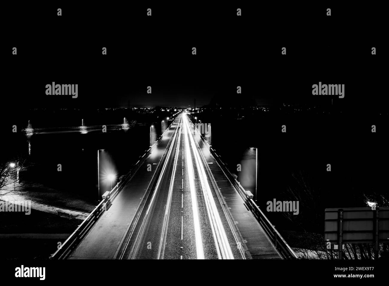 Long Exposure Auto Lichtspuren durch eine Brücke in einer kleinen Stadt während der Nacht Stockfoto
