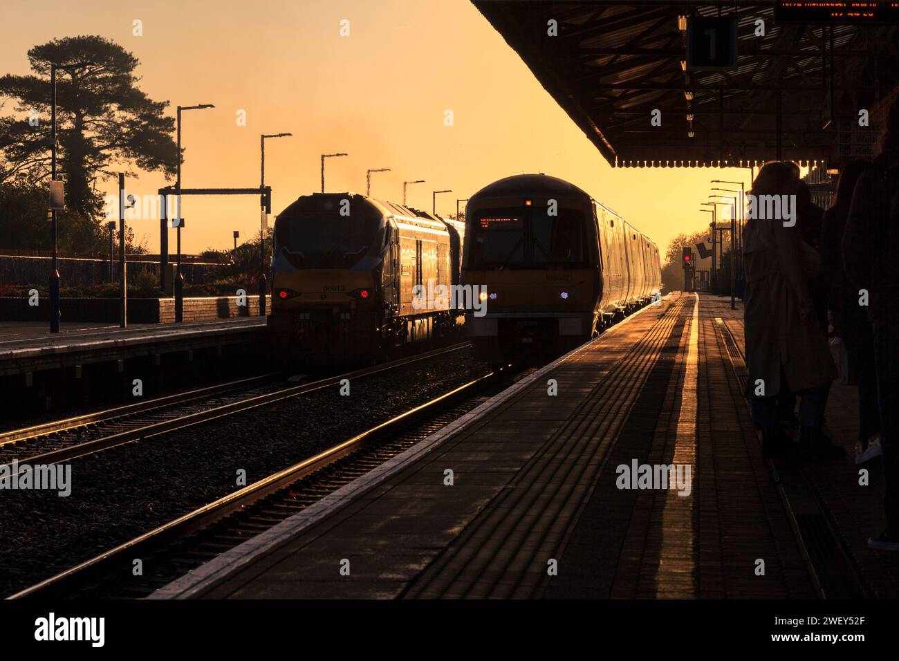 Chiltern Railways der Baureihe 68 Lokomotive 68013 und Baureihe 168 168002 am Bahnhof Bicester North, wo sie die aufgehende Sonne mit einem goldenen Glanz erstrahlen lassen Stockfoto