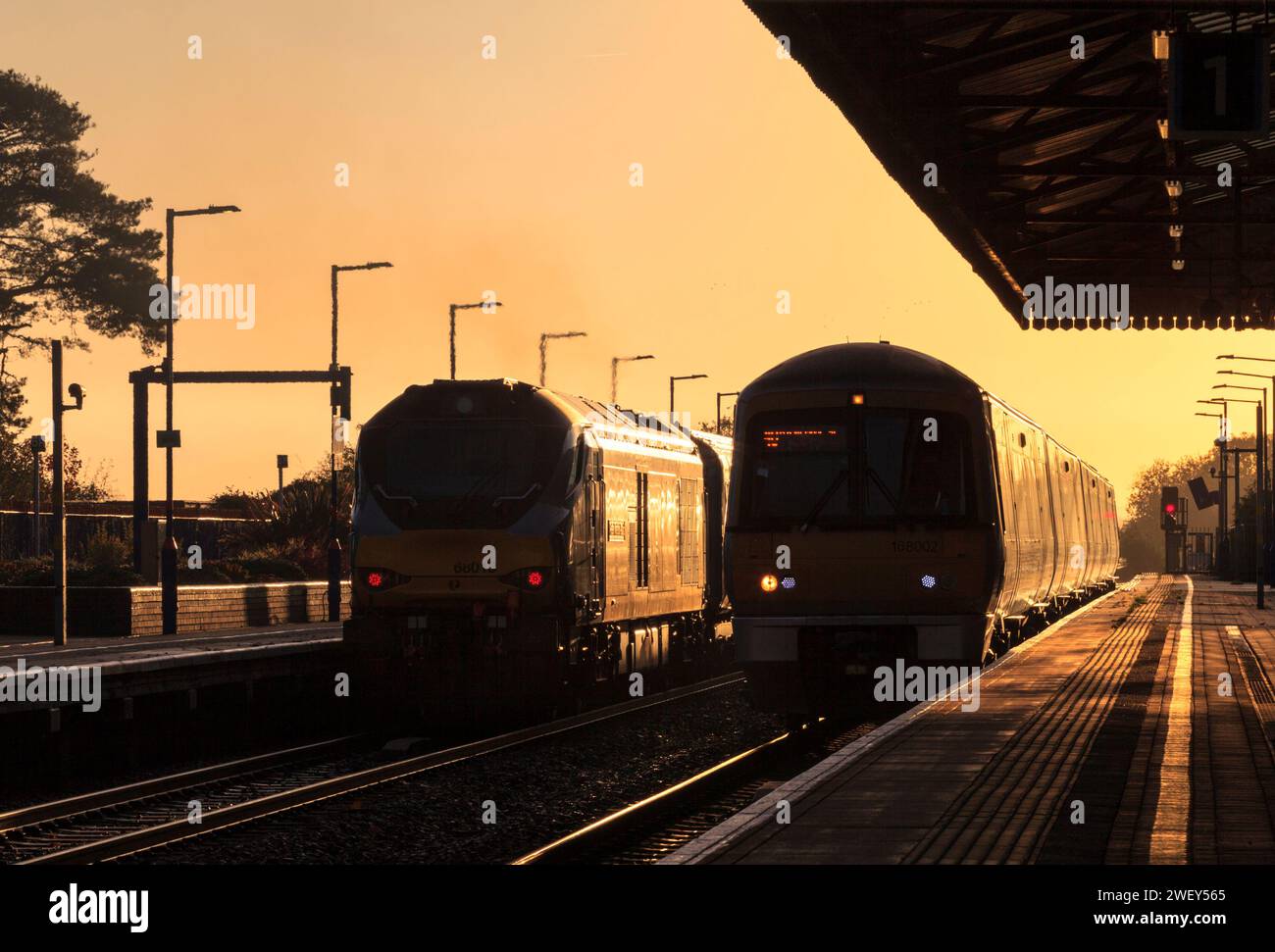 Chiltern Railways der Baureihe 68 Lokomotive 68013 und Baureihe 168 168002 am Bahnhof Bicester North, wo sie die aufgehende Sonne mit einem goldenen Glanz erstrahlen lassen Stockfoto