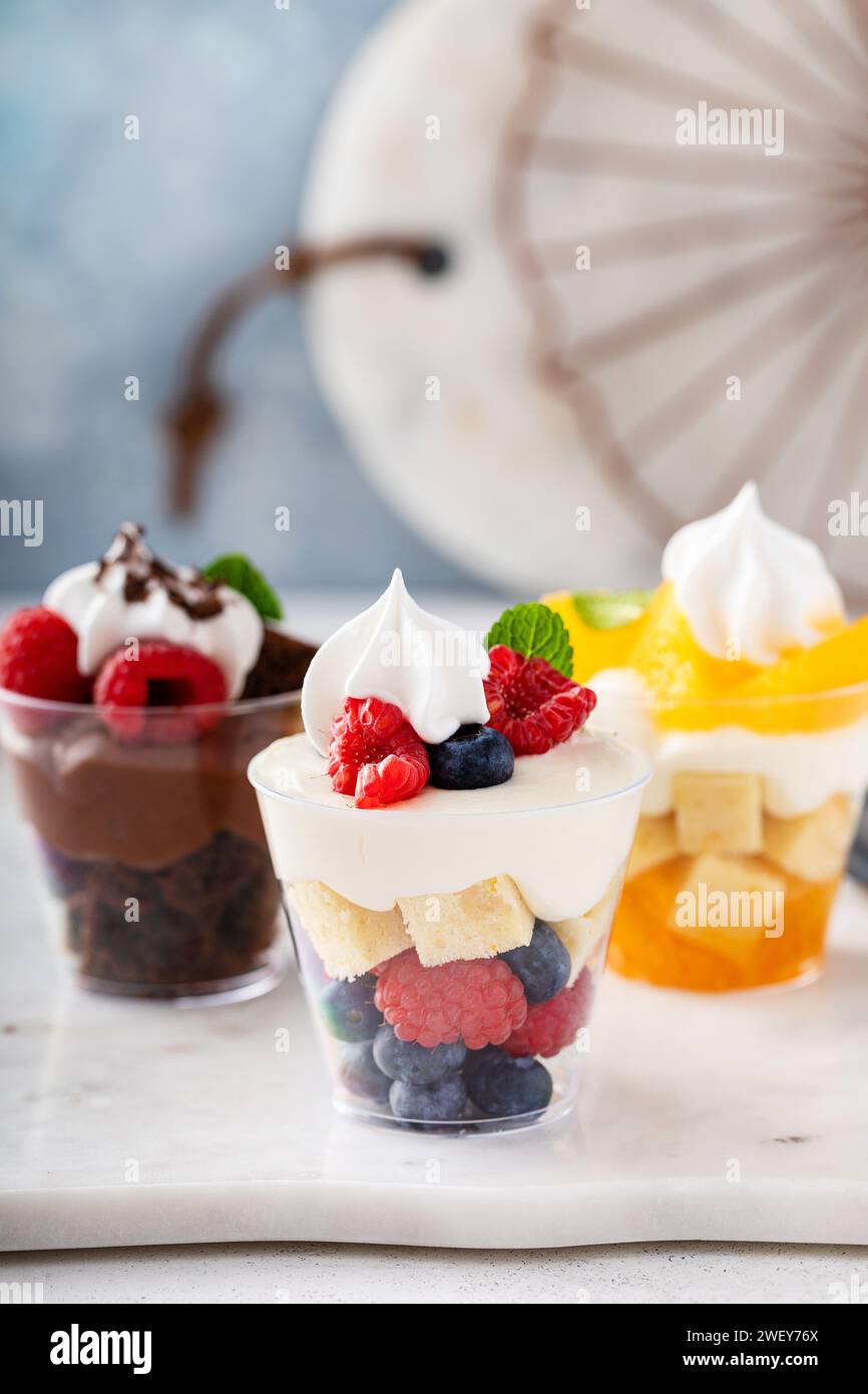 Drei Desserts in Tassen, verschiedene Kleinigkeiten mit Orangen-, Schokoladen- und Beerenkuchen Stockfoto