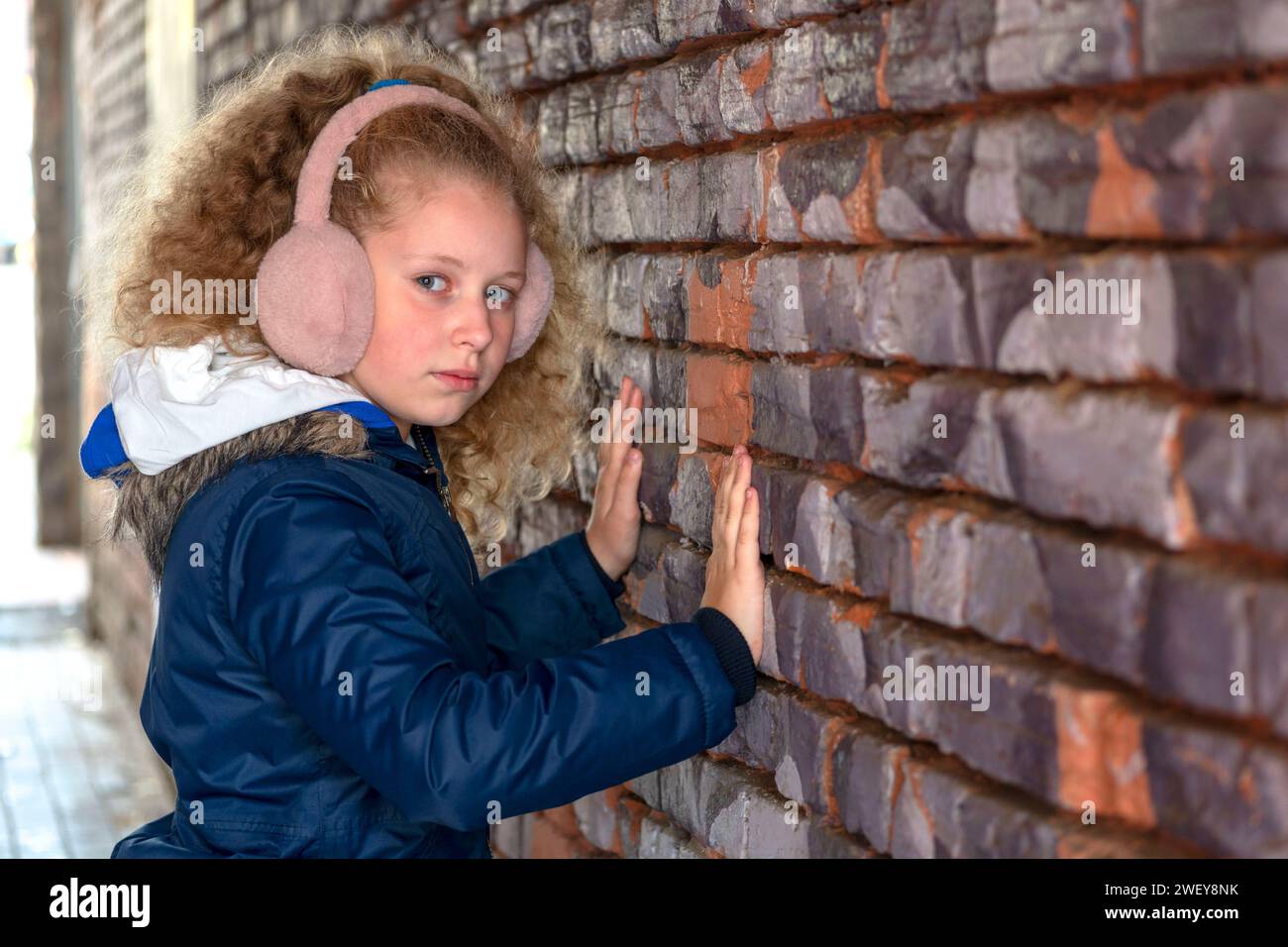 Mädchenhand in der Lücke der Wand. Der Teenager greift zum Mauerloch. Kind an der Ziegelmauer. Das Konzept von Stille, Rätsel, Spannung, Interesse Depr Stockfoto