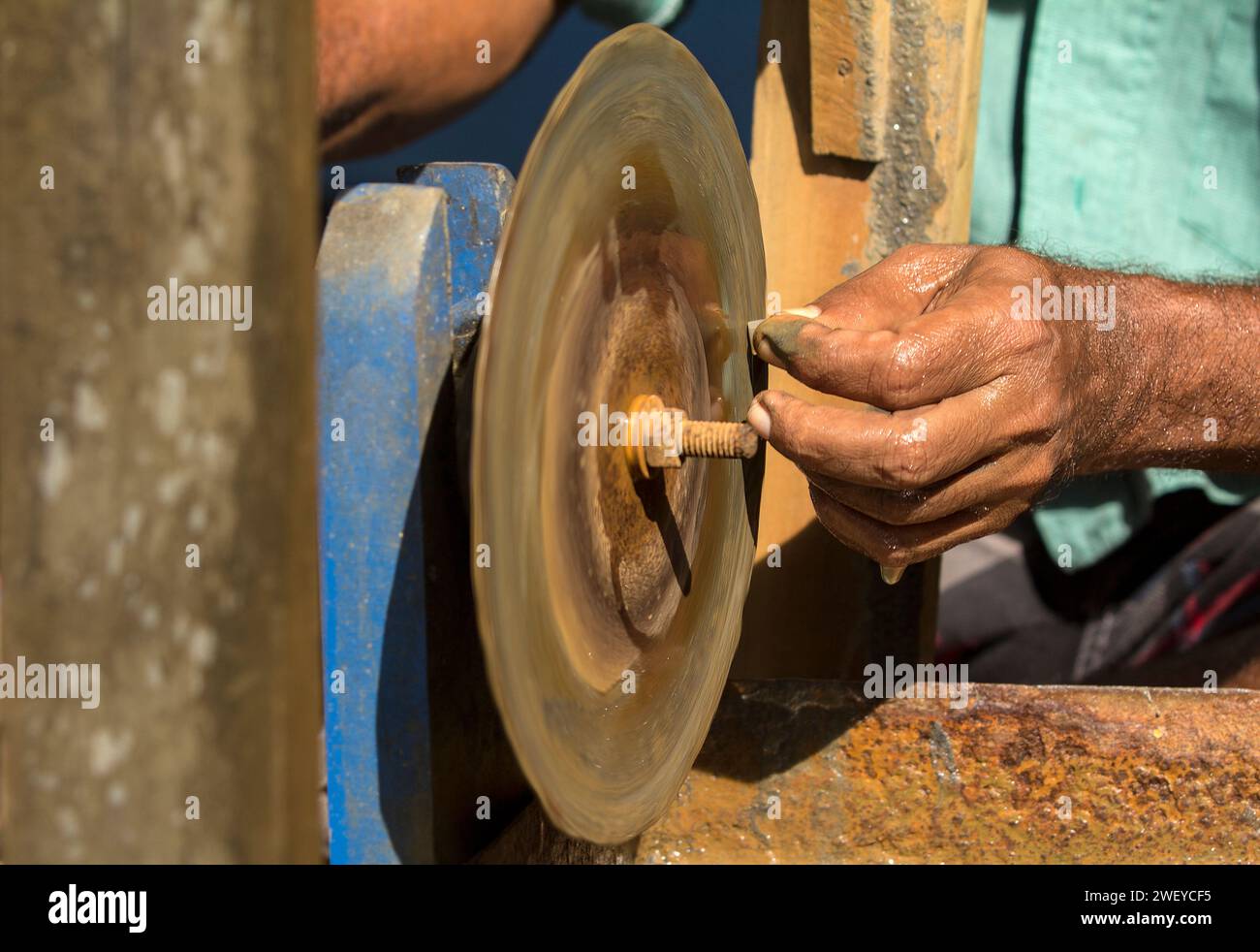 Nahaufnahme der Hand eines Mannes, der ein Teil mit einer Maschine schärft. Geeignet für Kunsthandwerk und traditionelle Berufe in Sri Lanka Stockfoto