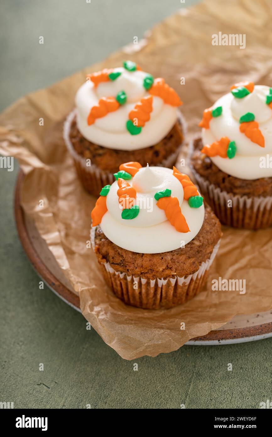 Karottenkuchen Cupcakes mit Frischkäse-Zuckerguss, dekoriert mit kleinen Karotten Stockfoto