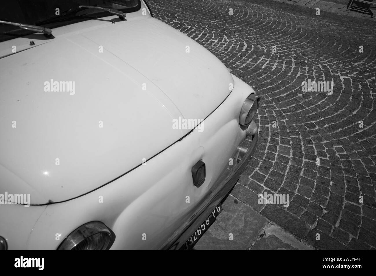 Gubbio Italien - 13. Mai 2011; Vorderseite eines kleinen italienischen ikonischen Autos in Vogelperspektive auf der europäischen Kopfsteinpflasterstraße in Schwarzweiß. Stockfoto