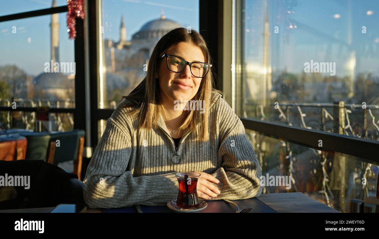 Eine junge Frau genießt Tee in einem Restaurant mit der hagia sophia im Hintergrund in istanbul, türkei. Stockfoto