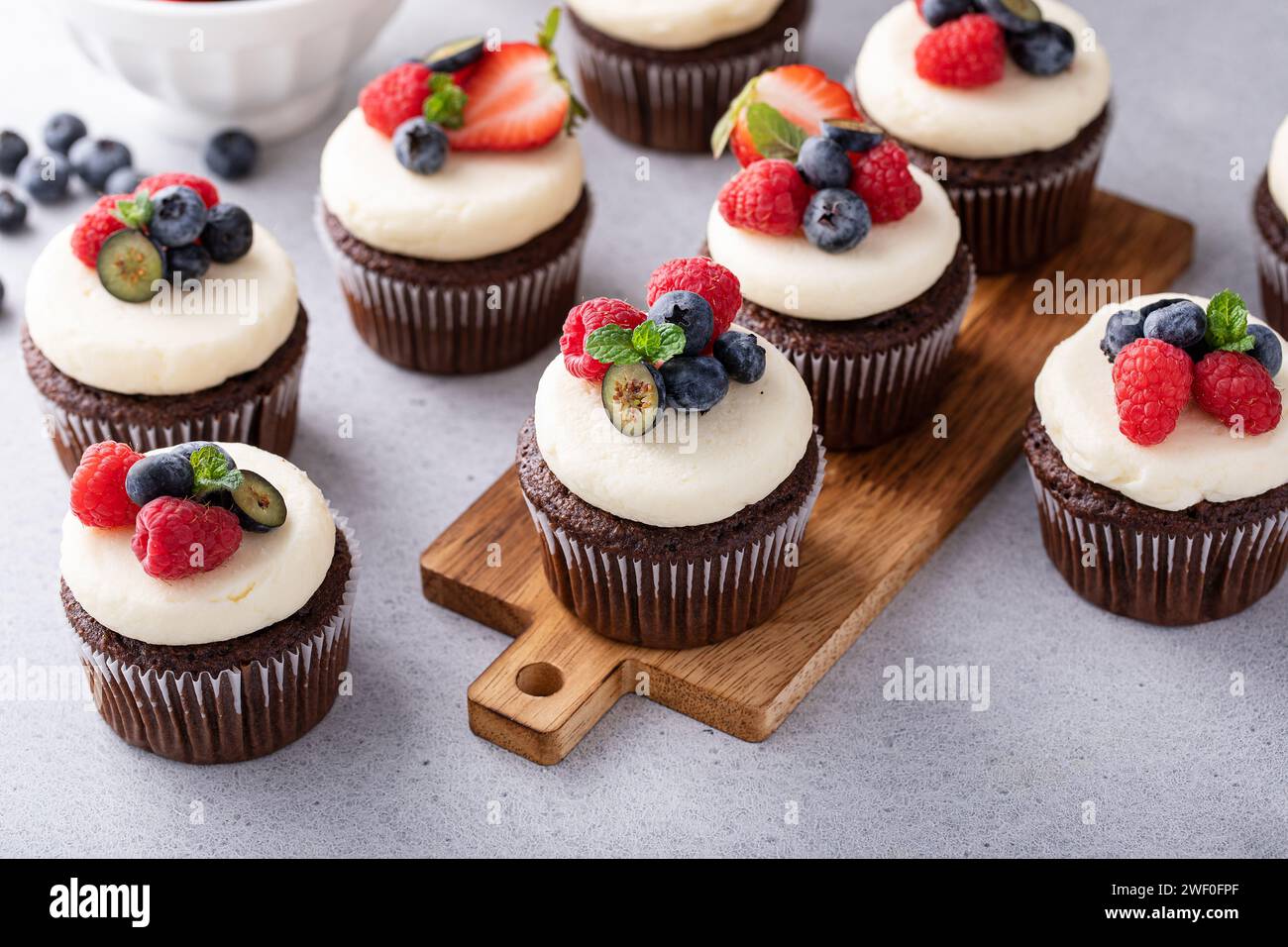 Schokoladen-Cupcakes mit Vanillefrosting und frischen Beeren darauf Stockfoto