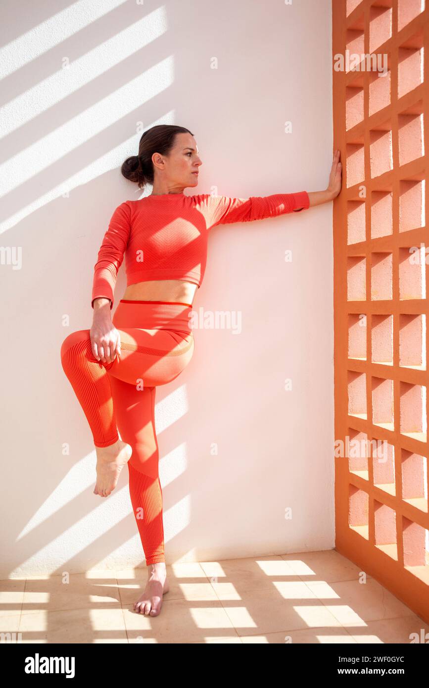 Eine sportliche Frau, die sich in Rückenlage dehnt, Wand Pilates Übungen macht. Stockfoto