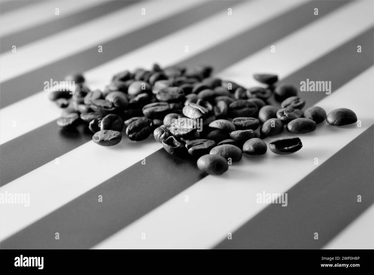 Schwarz-weiß-Foto von Kaffeebohnen auf gestreifter Tischplatte Stockfoto
