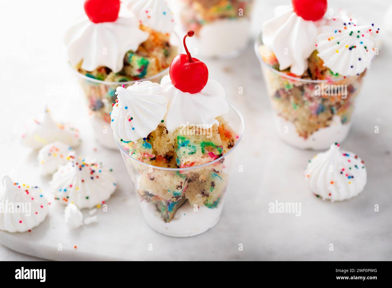Funfetti-Kuchen in einer Tasse mit Schlagsahne, Streuseln und Kirsche darauf Stockfoto