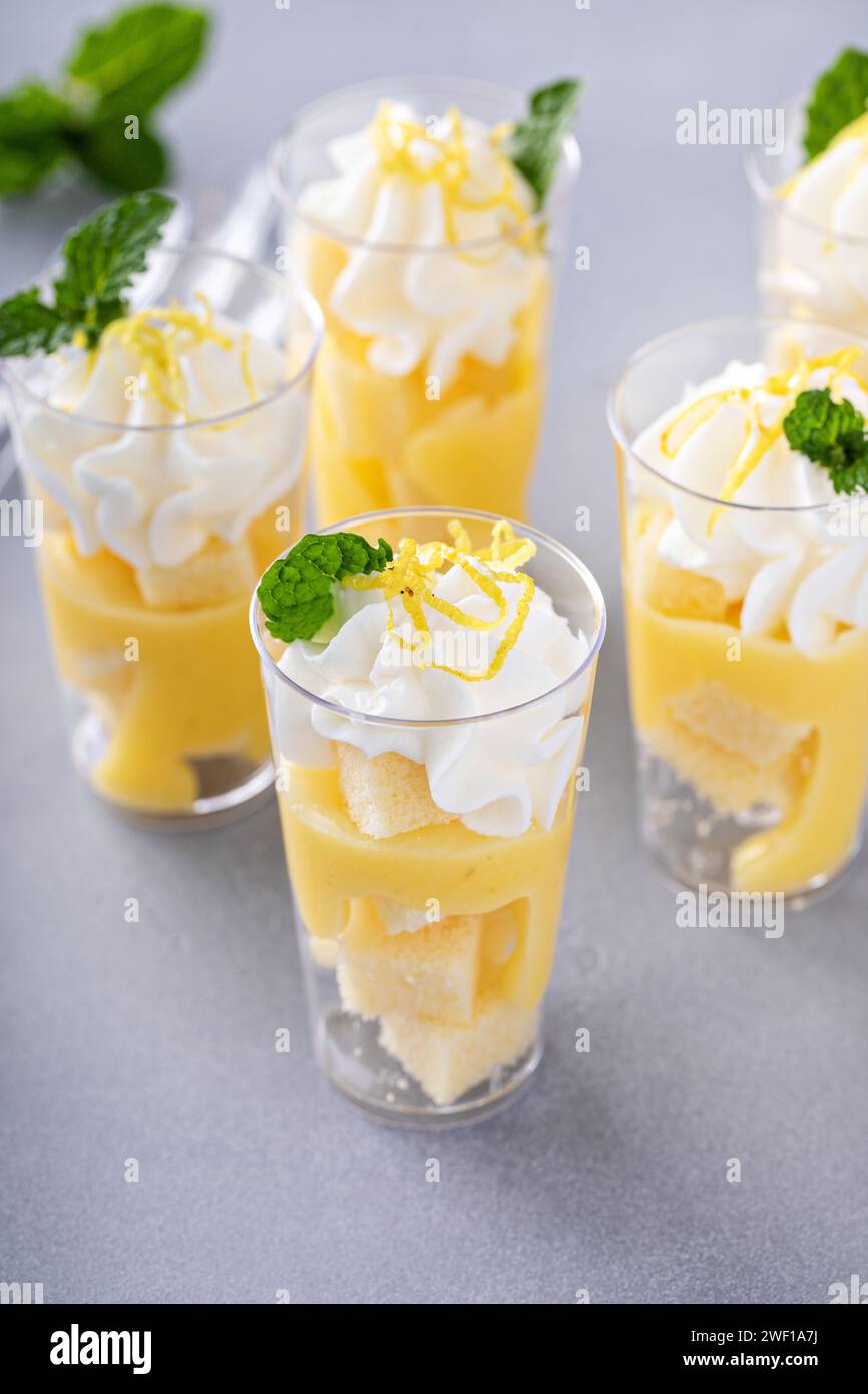 Zitronenmeringue-Parfaits in kleinen Tassen mit Pfund-Kuchen und Schlagsahne Stockfoto