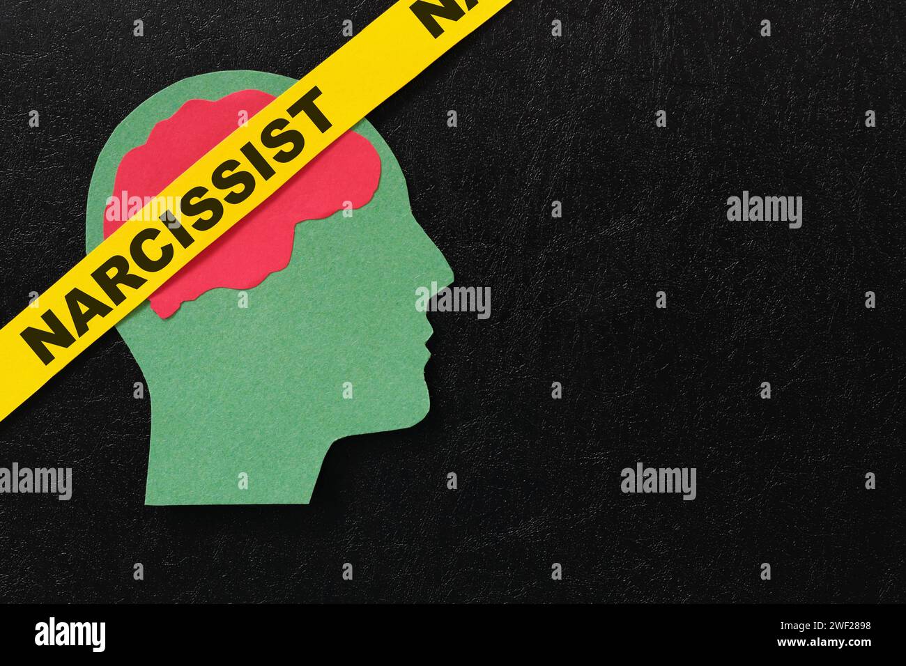 Menschliches Kopfprofil mit Wort Narzisst auf dunkelschwarzem Hintergrund. Narzisstisches Verhaltenskonzept. Stockfoto