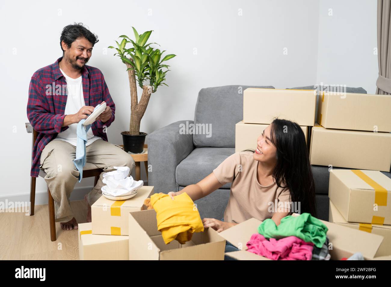 Asiatische Liebhaber, die in ein neues Haus gezogen sind. Liebhaber, die ihr Gepäck gerne organisieren. Stockfoto
