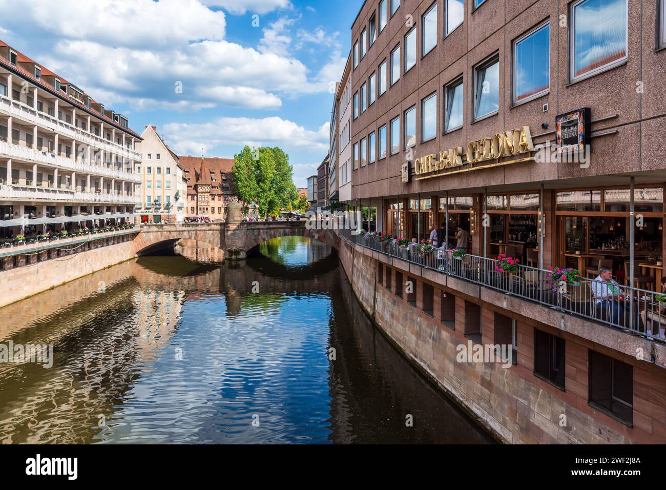 Stadtbild in der Altstadt von Nürnberg, mit Straßencafés entlang der Pegnitz, der Museumsbrücke und dem Heilig-Geist-Spital. Stockfoto