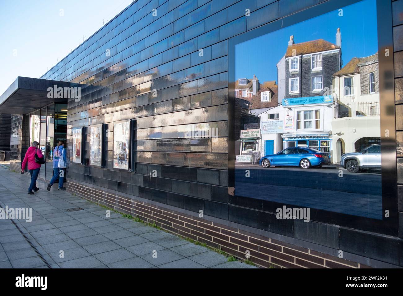 Hastings Contemporary Art Gallery, die das schwarz gekachelte Lavender House gegenüber in East Sussex, Großbritannien, widerspiegelt Stockfoto