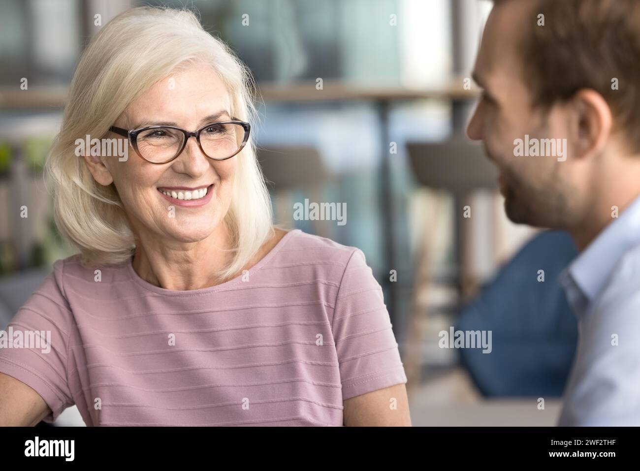 Glückliche attraktive Geschäftsfrau, die mit jüngeren Kollegen spricht Stockfoto